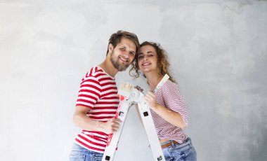 Genç çift yeni evlerinin duvarlarında resim.