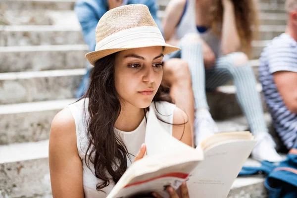 Bir kitap okuma taş basamaklar üzerinde oturan genç öğrenci kız. — Stok fotoğraf