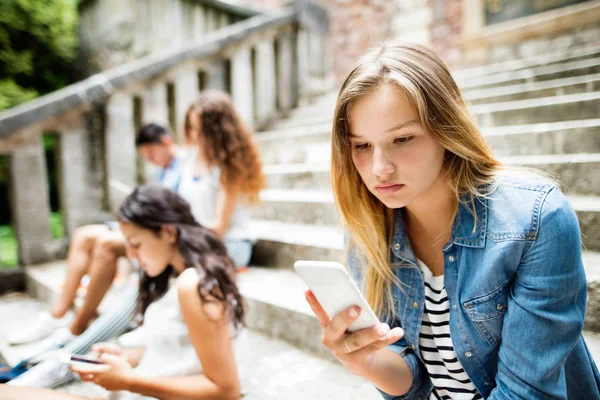 Adolescente estudiante chica con teléfono inteligente sentado en escalones de piedra . —  Fotos de Stock