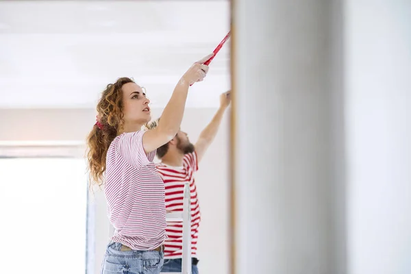 Jovem casal paredes de pintura em sua nova casa . — Fotografia de Stock