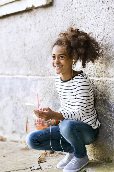 Menina americana africana bonita com telefone inteligente e bebida . — Fotografia de Stock