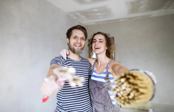 Young couple in love painting walls in their new home.