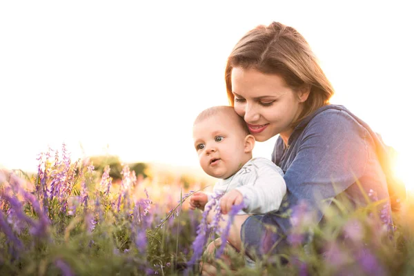 腕の中で赤ん坊の息子と自然で若い母親. — ストック写真