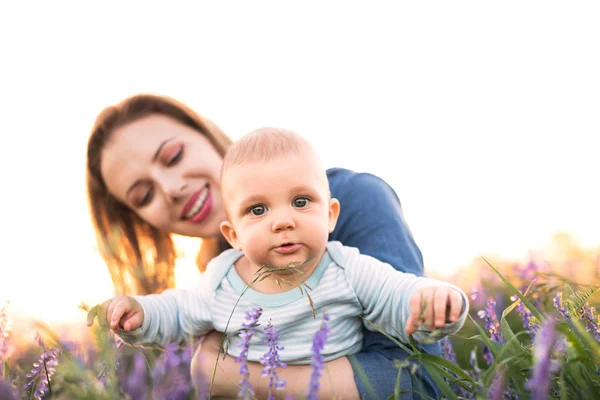 Jeune mère dans la nature avec bébé fils dans les bras . — Photo