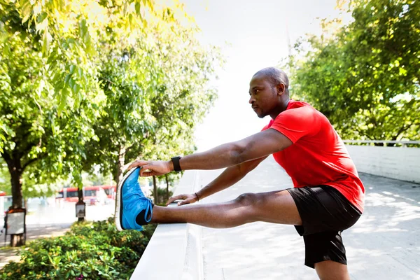 Молодой афро-американский бегун в городе разминает ноги . — стоковое фото