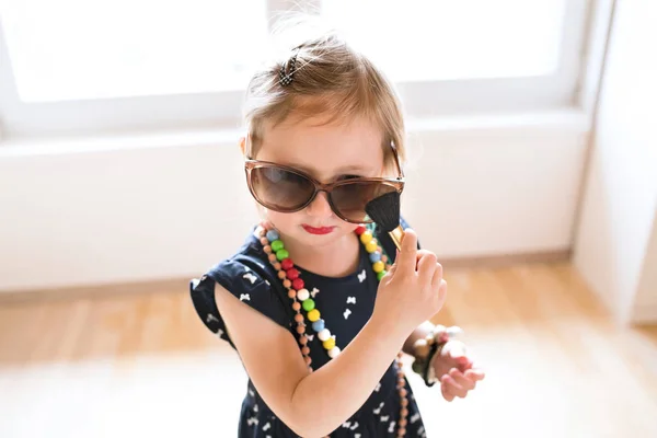 Linda niña en vestido y gafas de sol grandes en casa . —  Fotos de Stock