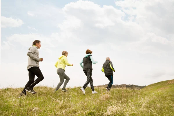 Grupo de idosos correndo fora nas colinas verdes . — Fotografia de Stock