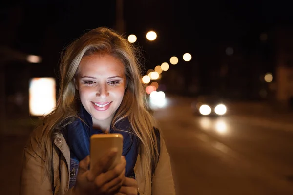 Kvinna i staden på natten innehav smartphone, textning. — Stockfoto