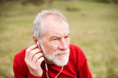 Akıllı telefon ve kulaklık ile doğada aktif kıdemli koşucu.