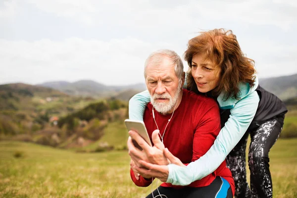 Corredores senior activos en la naturaleza tomando fotos con un teléfono inteligente . — Foto de Stock