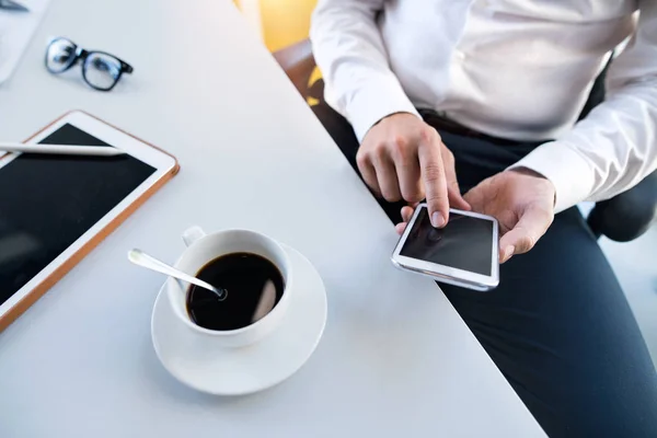 Zakenman met smartphone en tablet in zijn kantoor. — Stockfoto