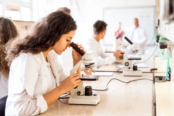 Estudante do ensino médio bonito com microscópio em laboratório . — Fotografia de Stock