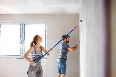 Genç çift yeni evlerinin duvarlarında resim.
