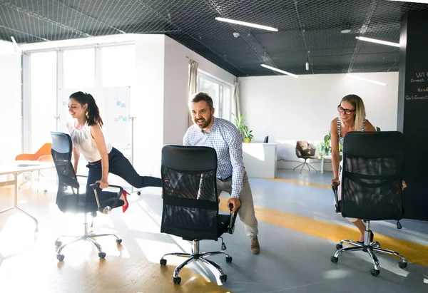 Empresários montando uma cadeira e correndo no local de trabalho . — Fotografia de Stock