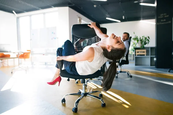 Business woman riding a chair and racing in the workplace. — Stock Photo, Image