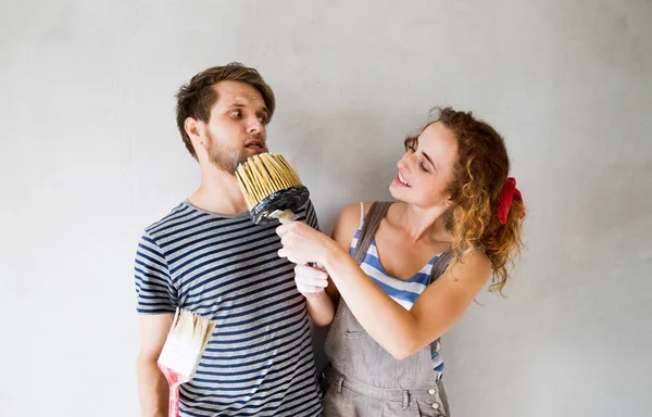 Pareja joven enamorada pintando paredes en su nuevo hogar . — Foto de Stock