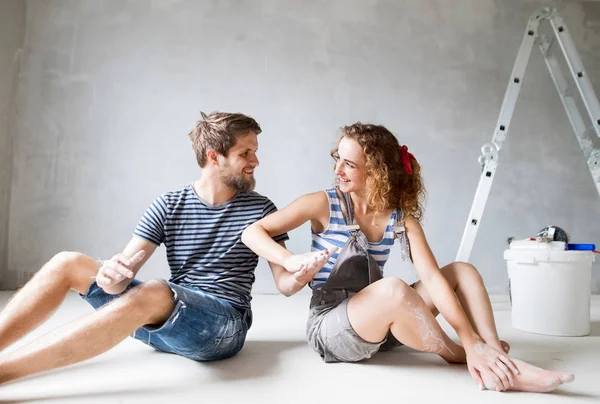 Pareja joven pintando paredes en su nueva casa . — Foto de Stock