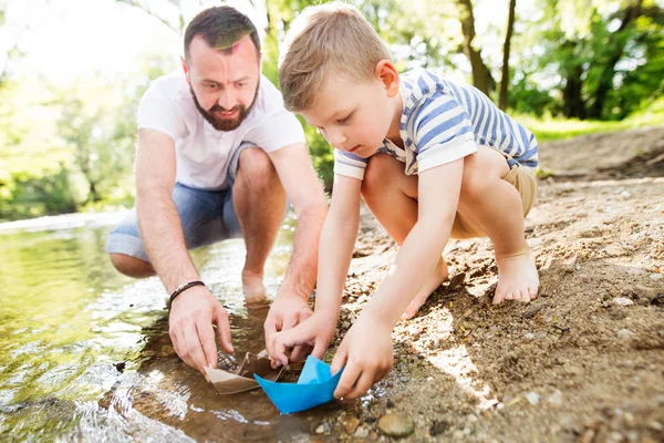 Jovem pai com menino no rio, dia ensolarado da primavera . — Fotografia de Stock