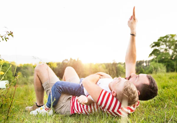 Hipster father and little son on green meadow. Sunny summer day. — Stock Photo, Image