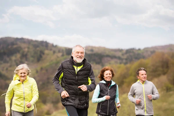 Seniorengruppe rennt draußen auf grünen Hügeln. — Stockfoto