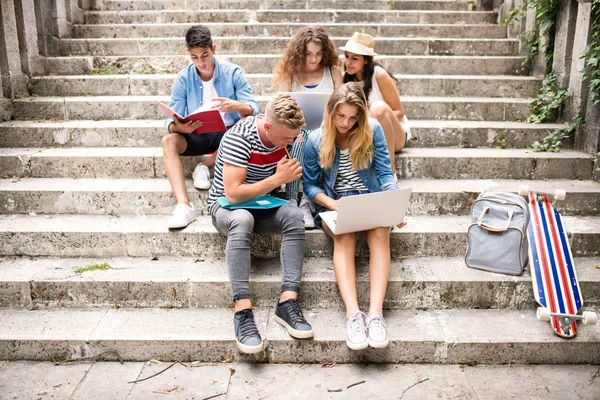 Teenage studenti s notebookem venku na kamenných schodech. — Stock fotografie