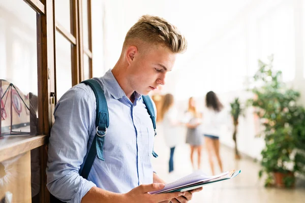 Tonårspojke med anteckningsböcker i gymnasiet hall under paus. — Stockfoto