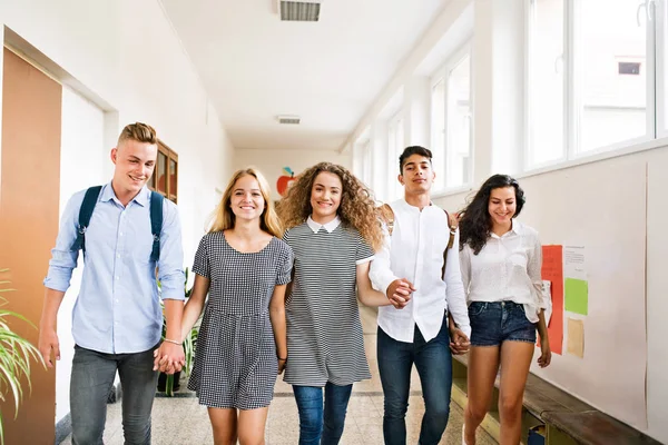 Tiener studenten lopen in high school hal, hand in hand. — Stockfoto