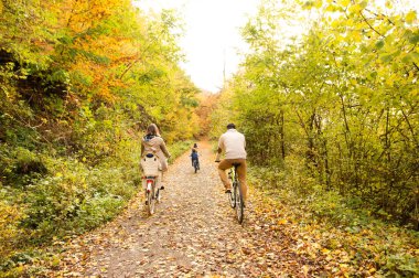 Genç aile içinde sıcak giysiler sonbahar parkta Bisiklete binme