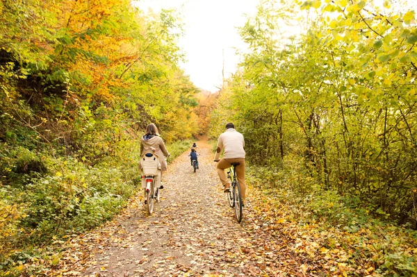 Młode rodziny w ciepłe ubrania na rowerze w parku jesień — Zdjęcie stockowe