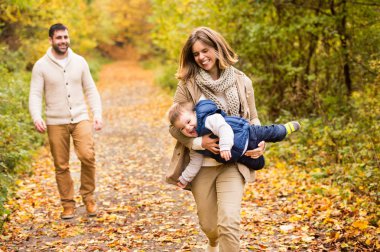 Güzel genç aile sonbahar ormandaki bir yolda.