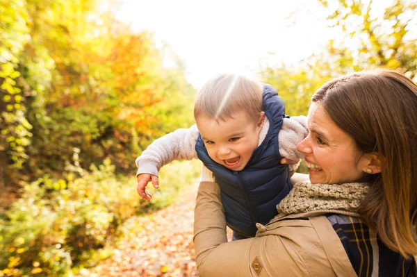 Beautiful young mother with her son in autumn forest. — Stock Photo, Image