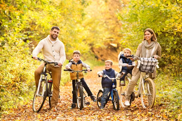 Young family in warm clothes cycling in autumn park — Stock Photo, Image