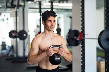 Kettlebell ile egzersiz spor salonunda İspanyol adam genç yerleştirmek.