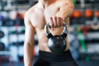 Tanınmayan genç adam kettlebell ile egzersiz spor salonunda yerleştirmek.