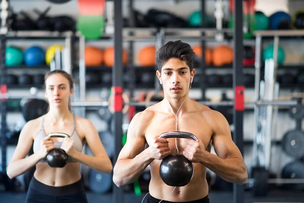 Jeune couple en forme dans la salle de gym exercice avec kettlebell . — Photo