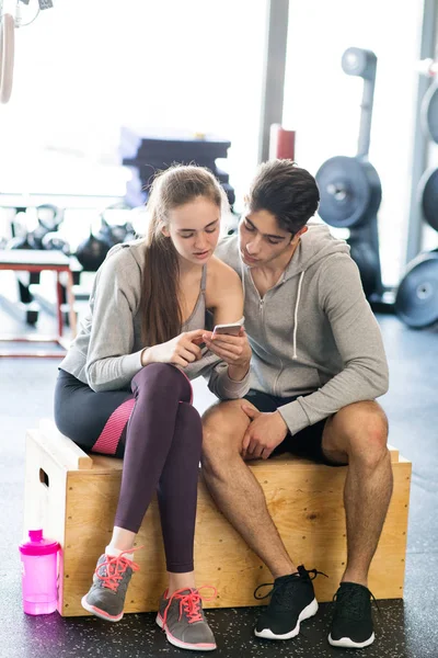 在现代的运动量来找到健身房与智能手机适合情侣. — 图库照片