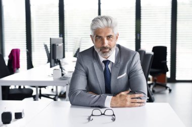 Ofiste gri elbiseli olgun iş adamı.