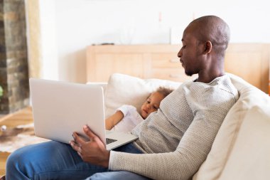 Afro-Amerikan baba küçük kızı ile evde laptop holding