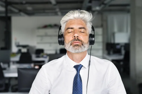 Maduro hombre de negocios con auriculares en la oficina . — Foto de Stock