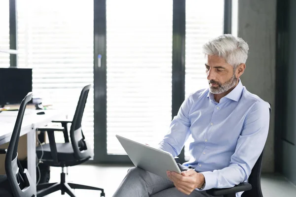 Rijpe zakenman met tablet in het kantoor. — Stockfoto