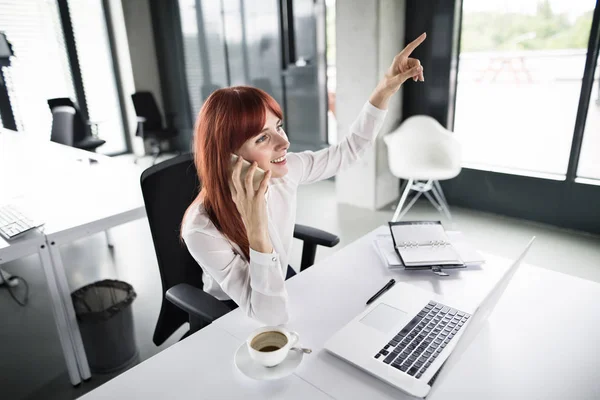 Bizneswoman z smartphone i laptopa w jej biurze. — Zdjęcie stockowe