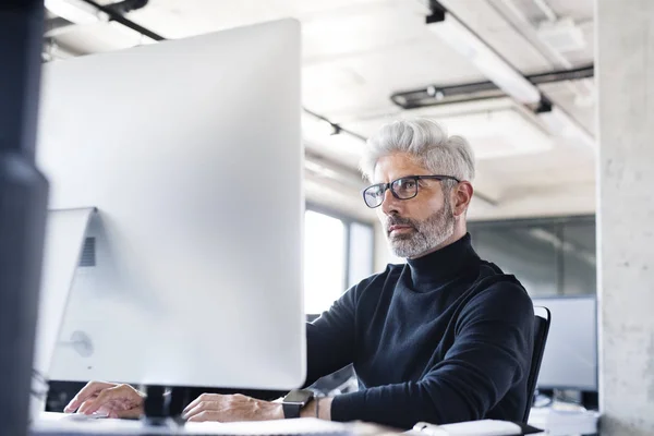 Mogen affärsman med dator på kontoret. — Stockfoto