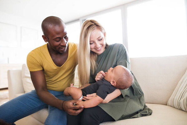 Young interracial family with little baby son at home.