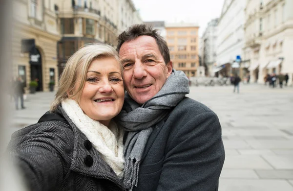 Hermosa pareja de ancianos en un paseo por el centro de la ciudad tomando selfie . —  Fotos de Stock