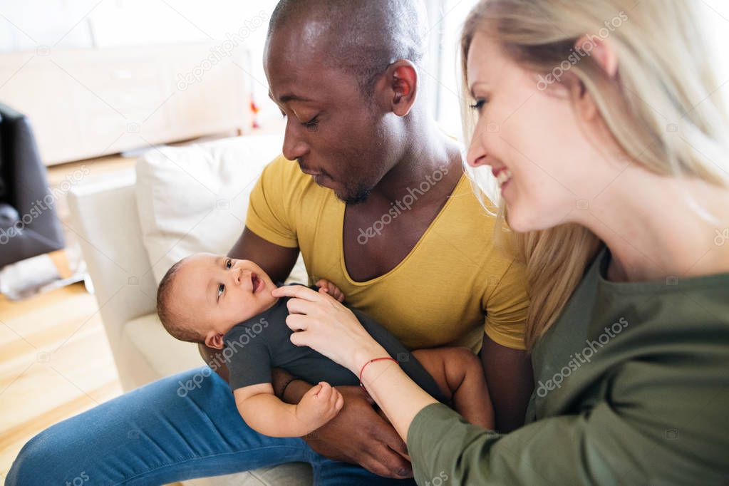 Young interracial family with little baby son at home.
