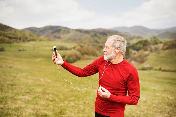 Aktiv senior löpare i naturen tar selfie med smart phone. — Stockfoto