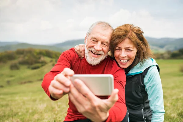 Corredores seniores ativos na natureza tirando fotos com telefone inteligente . — Fotografia de Stock