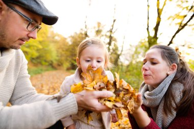 Güzel genç aile sonbahar ormandaki bir yolda.