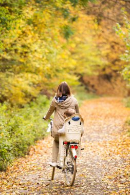 Genç anne oğluyla sonbahar parkta Bisiklete binme