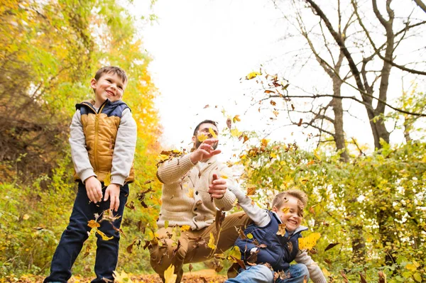 Junger Vater mit seinen Söhnen im Herbstwald. — Stockfoto